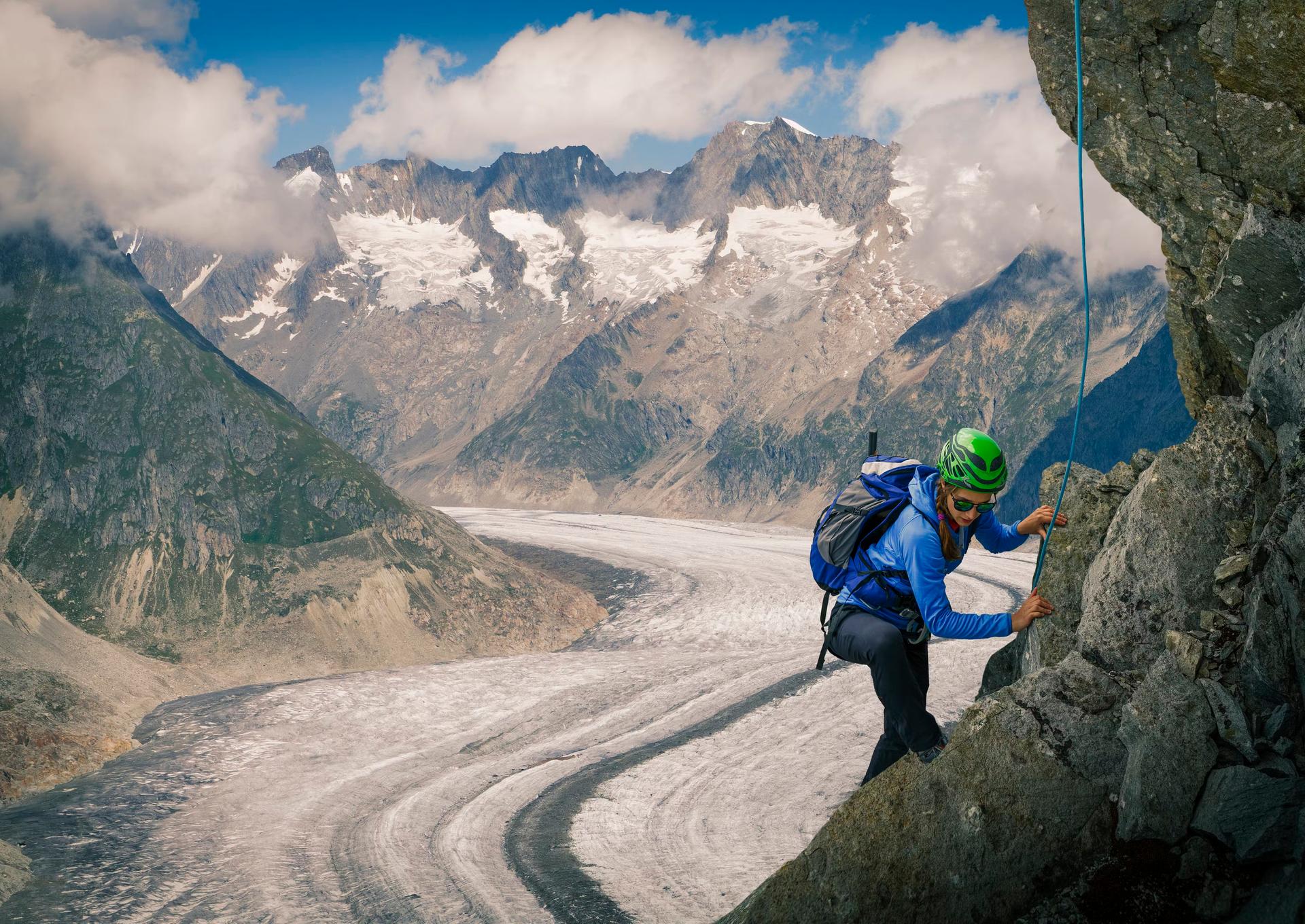 Climber on rock face over Aletsch Glacier in Switzerland