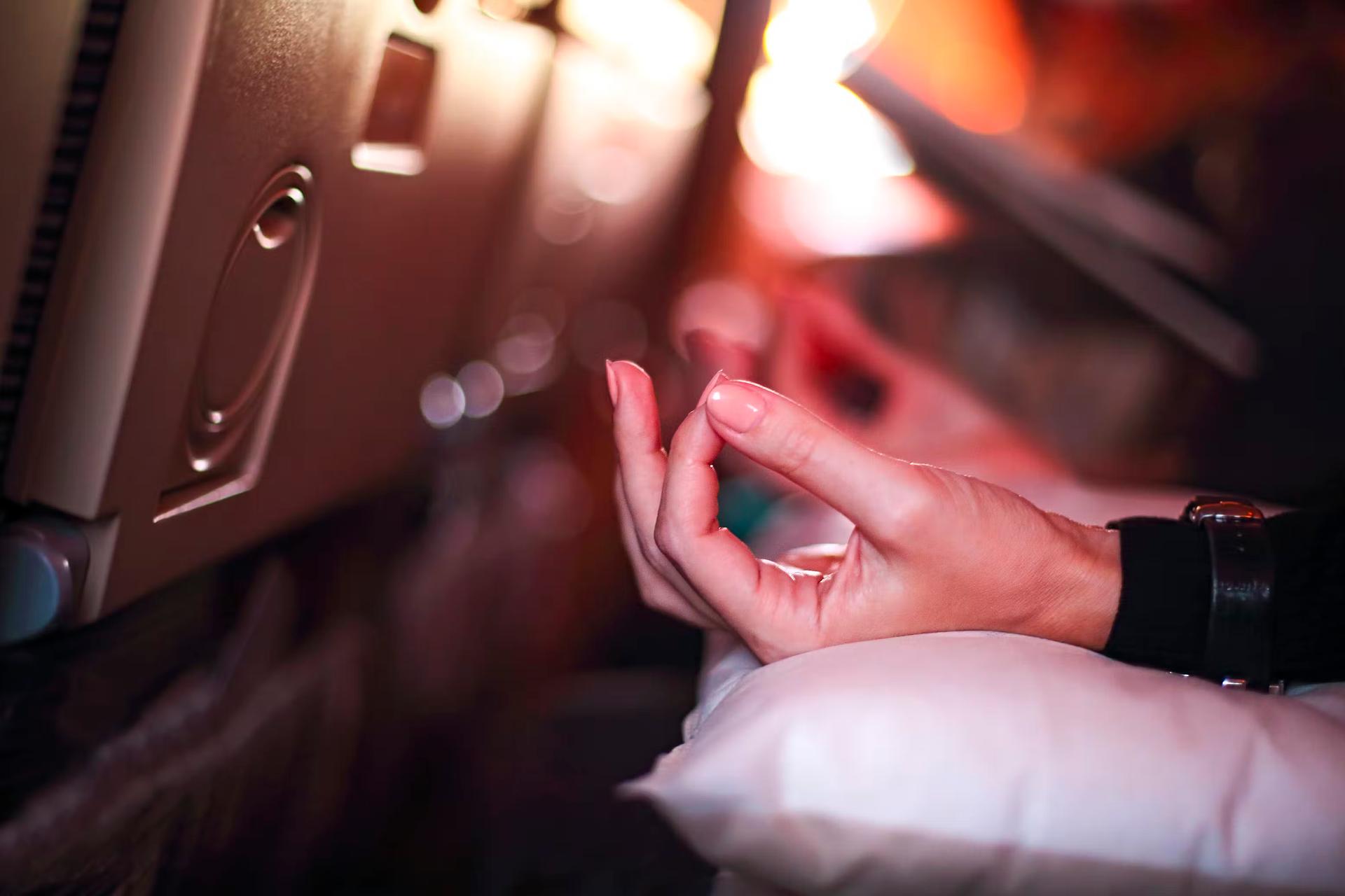 The hand of a person in an airplane doing yoga to relax
