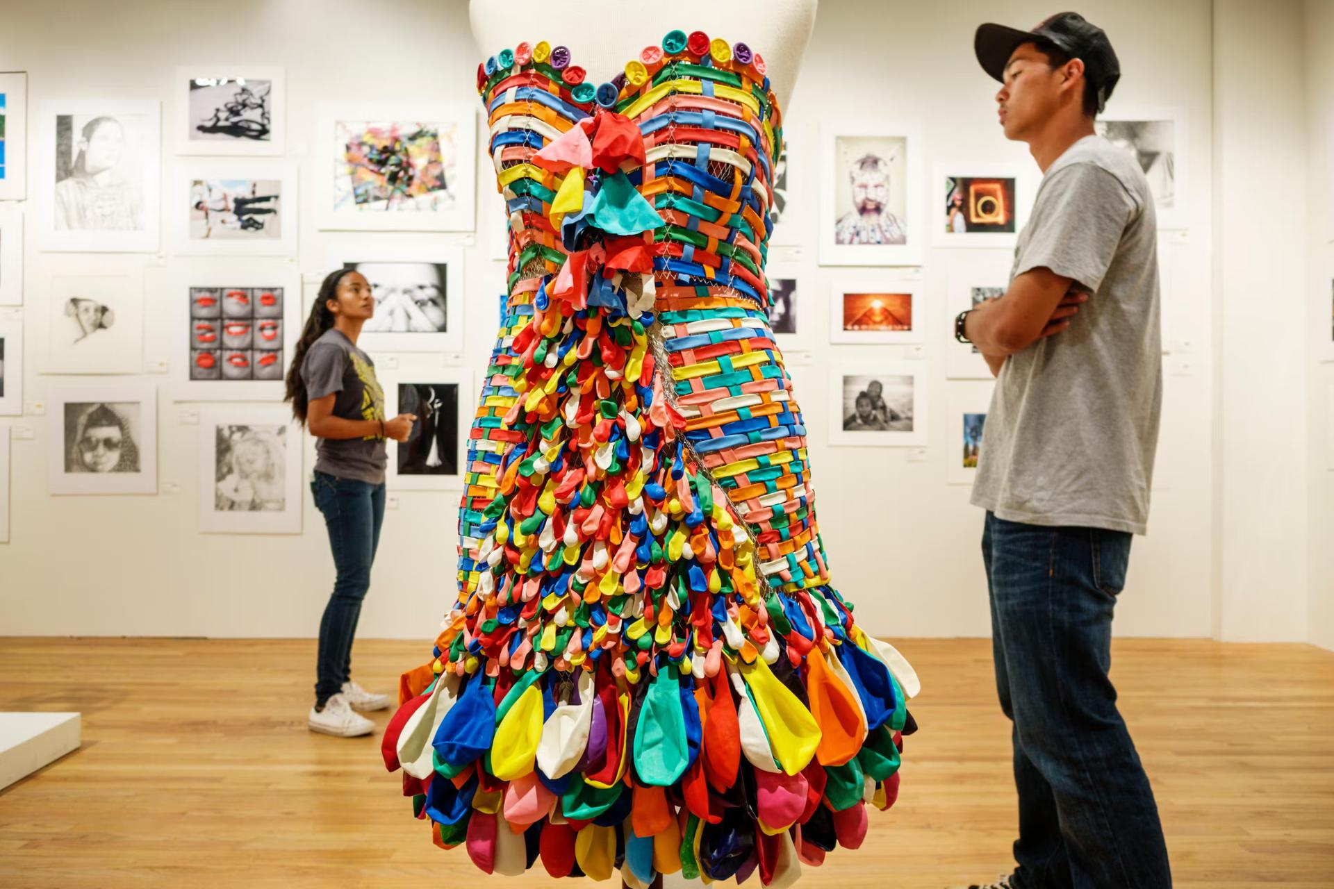 A man in a hat looks at a colorful dress in an art gallery in Hawaii