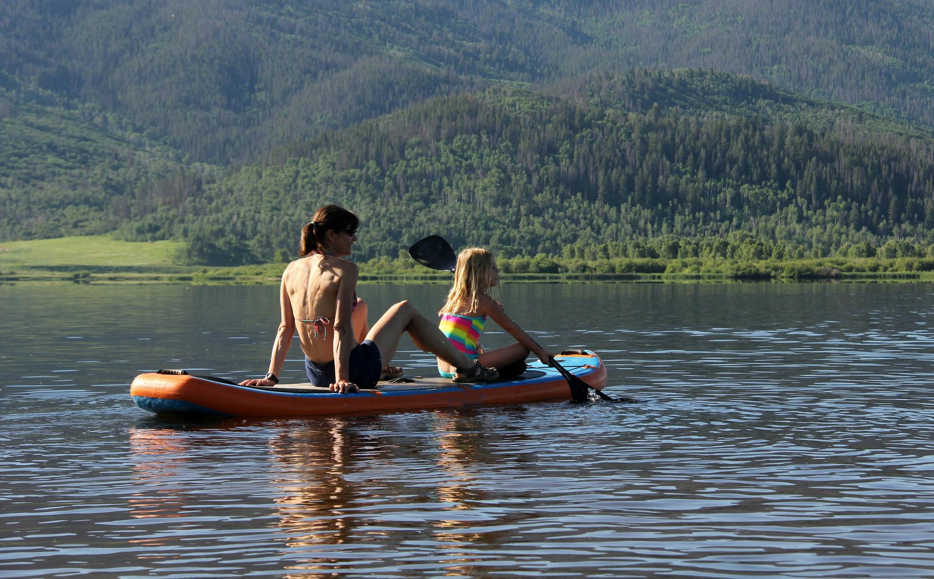 Mother and daughter Stand Up Paddle on alpine lake