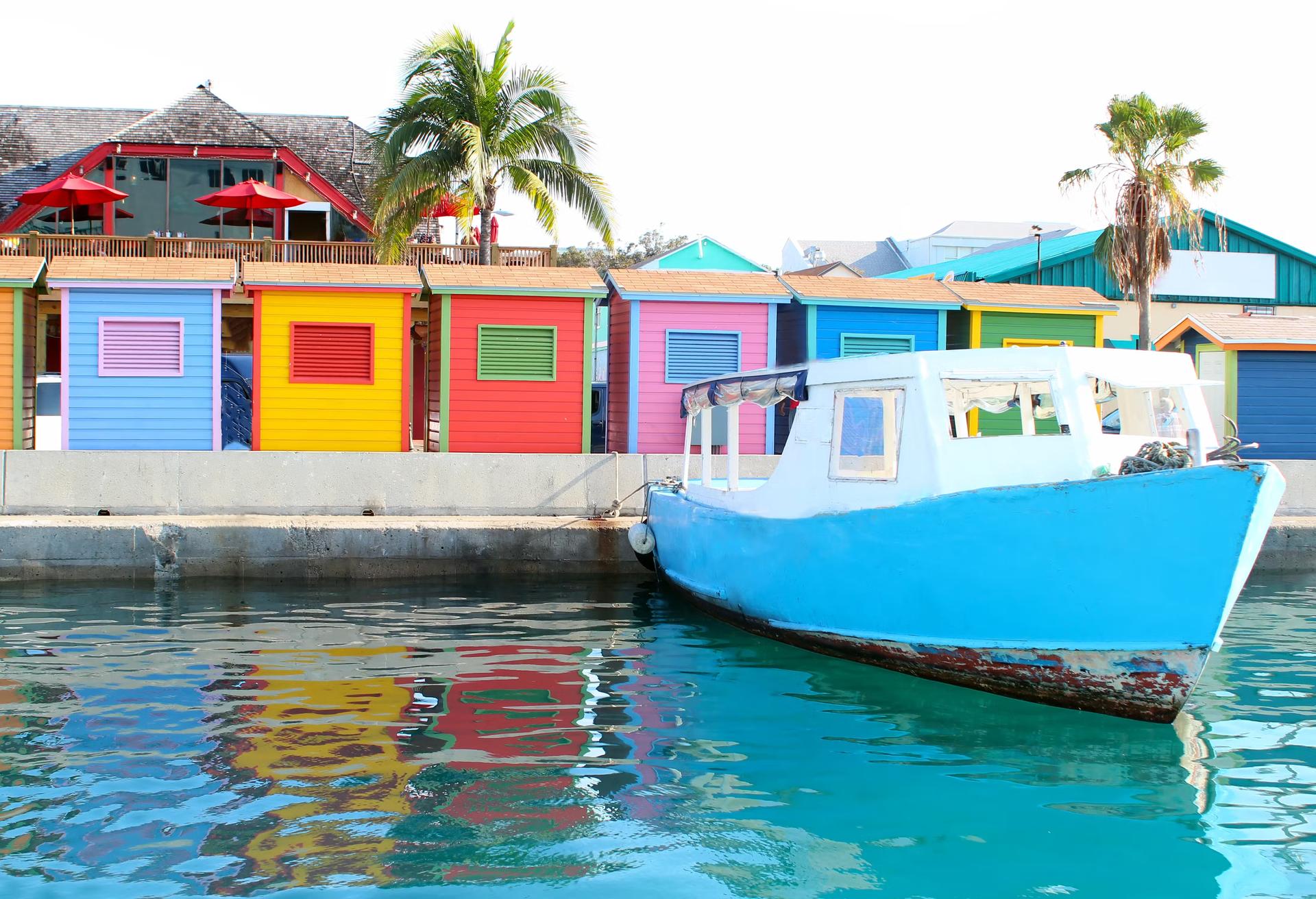 En färgstark bild av området vid vattnet i centrala Nassau som visar en vattentaxi och flera hyddor