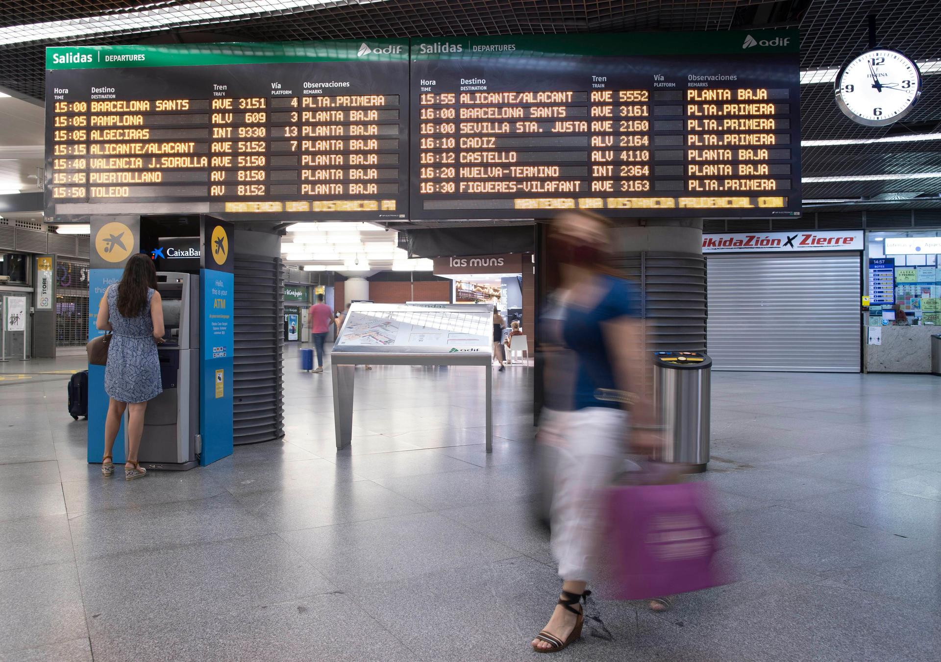 Passagerare vid avgångspanelen på AVE-stationen i Atocha, Madrid