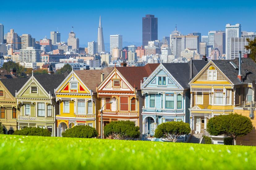 Classic postcard view of famous Painted Ladies, a row of colorful Victorian houses at scenic Alamo Square, with San Francisco skyline in the background on a beautiful sunny day with blue sky in summer