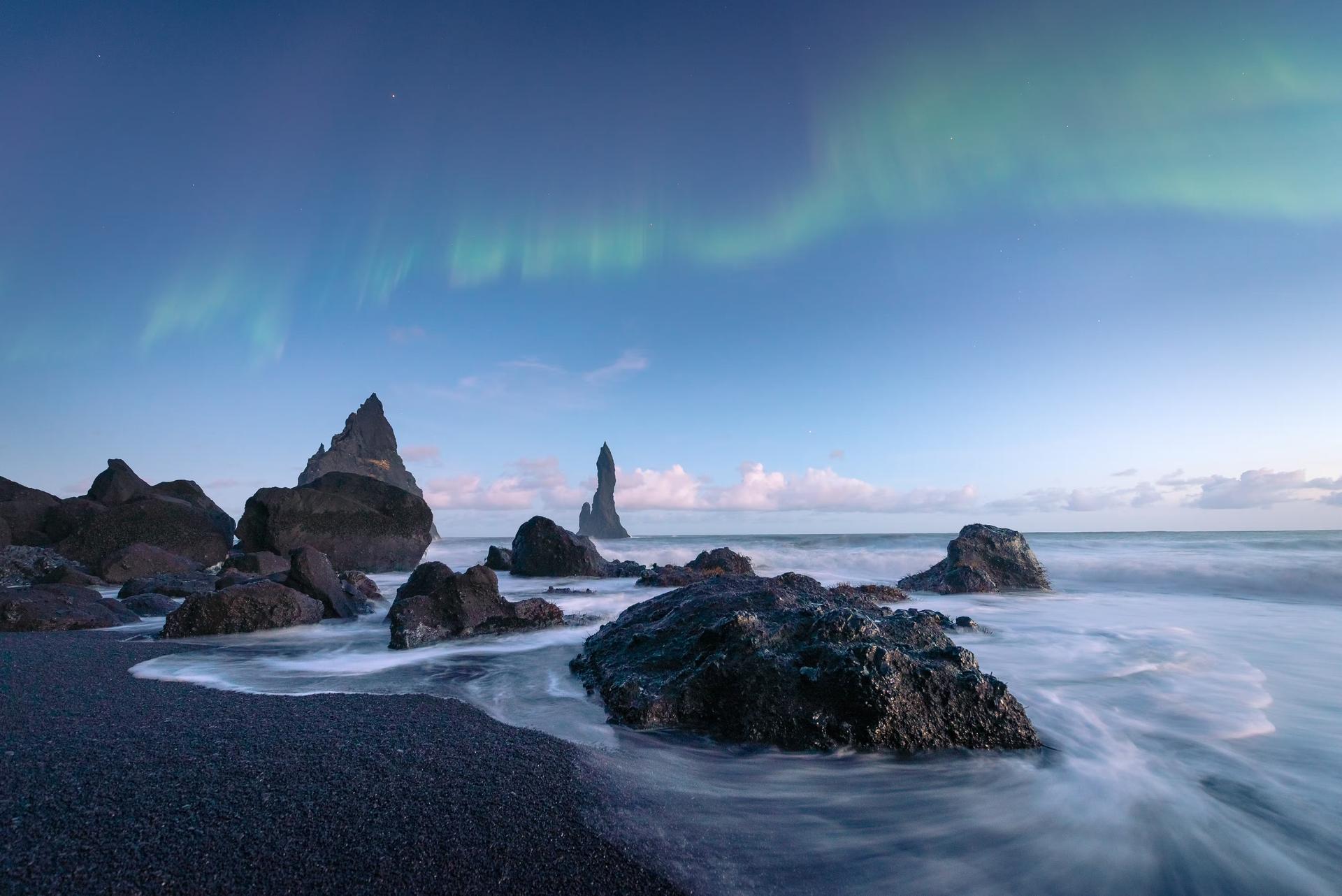 The black sand beaches of Iceland with the northern lights above. 