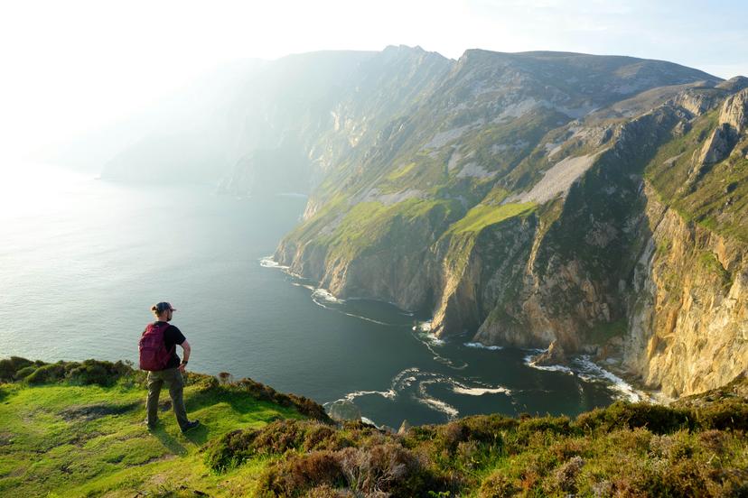 A male hiker looks over the cliffs of Slieve League, which is one of the most popular stops on the Wild Atlantic Way route.
