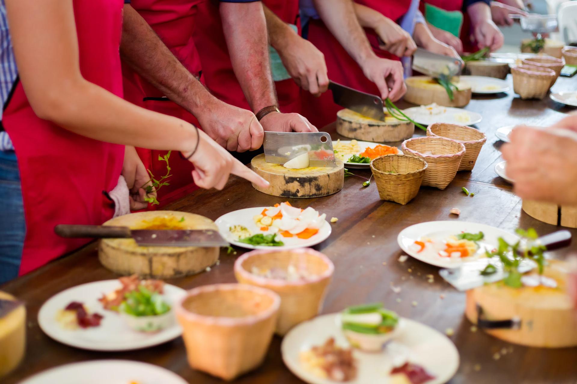 En närbild av händer som lagar mat vid ett långt bord