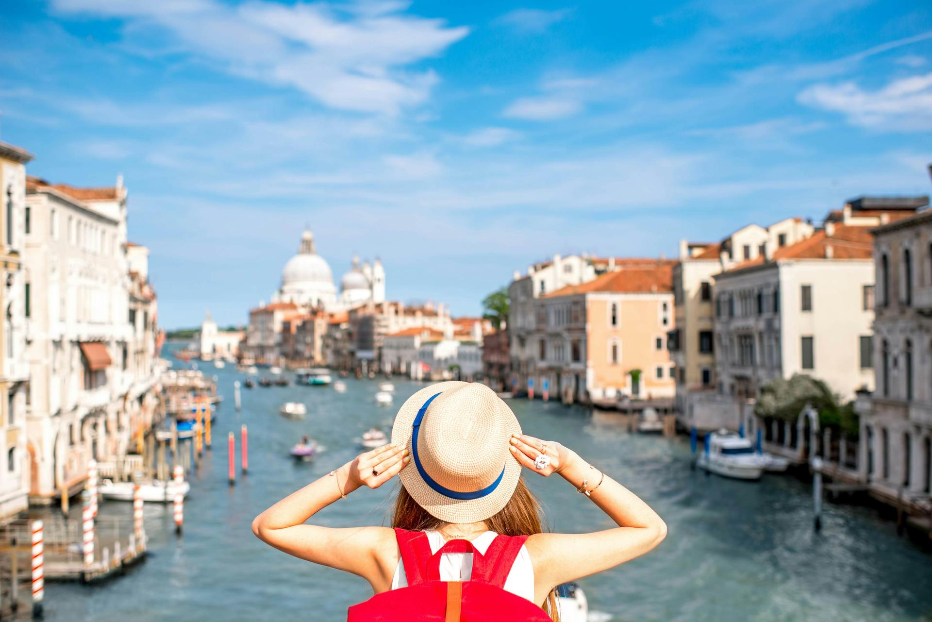 Canal Grande med kvinnlig resenär i hatt på Academia-bron i Venedig 