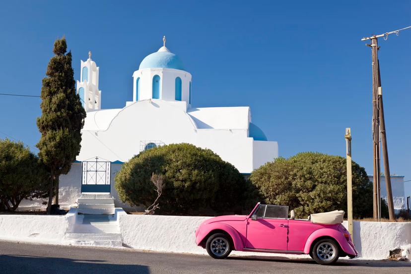 "Megalochori, Greece - September 4, 2011: A pink Volkswagen Beetle Convertible in front of a little chapel at the connection road between Megalochori and Fira"