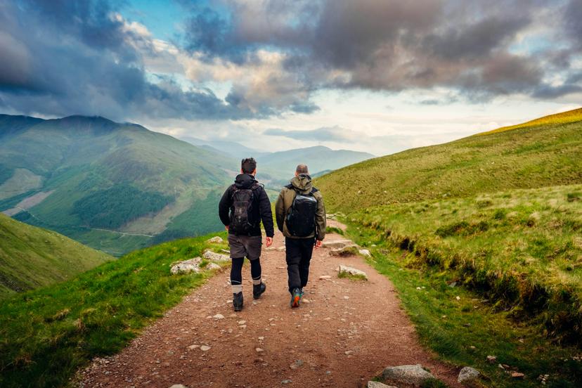 2 men pictured from the rear, walking along a hiking path on Ben Nevis in Scotland.