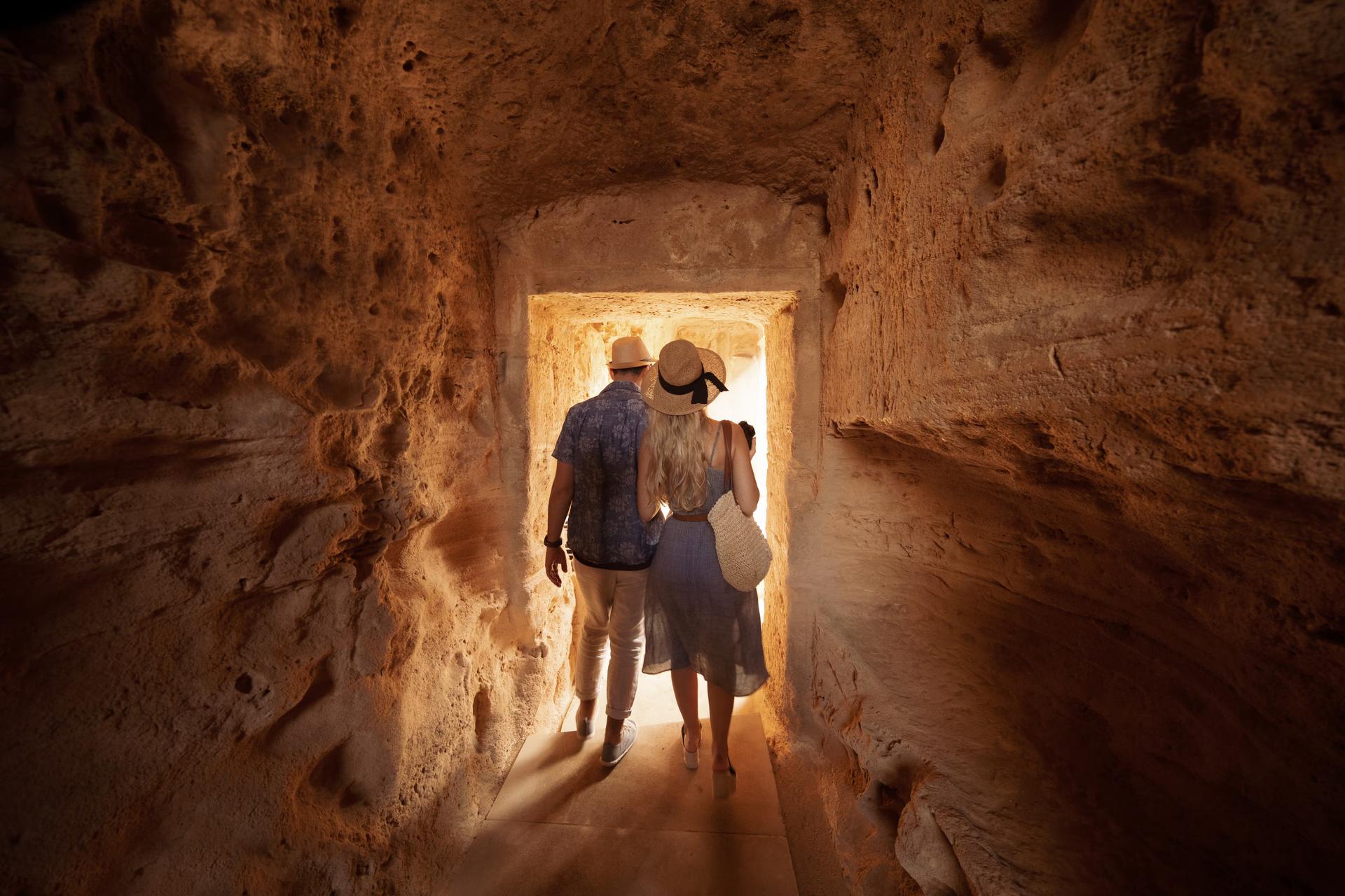 Tourists walking in dark passage at archaeological site in Cyprus. 
