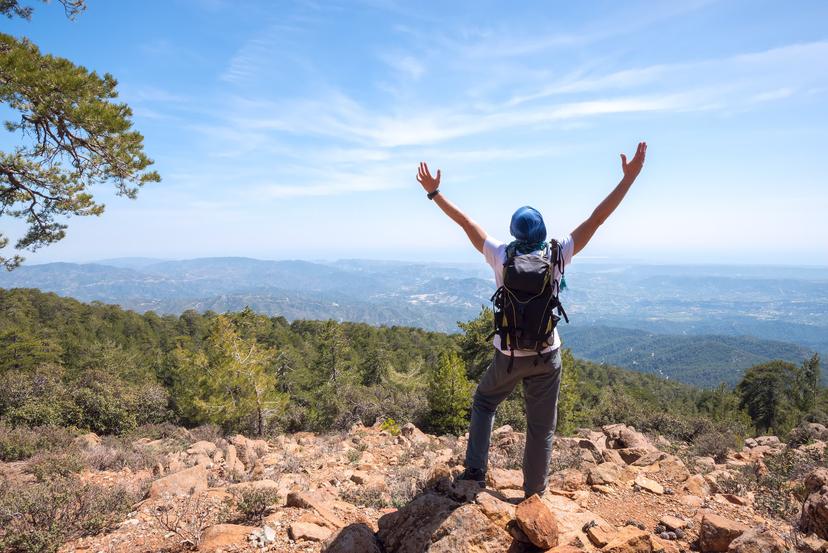 Hiker raising arms over views of mountains in Troodos National Park