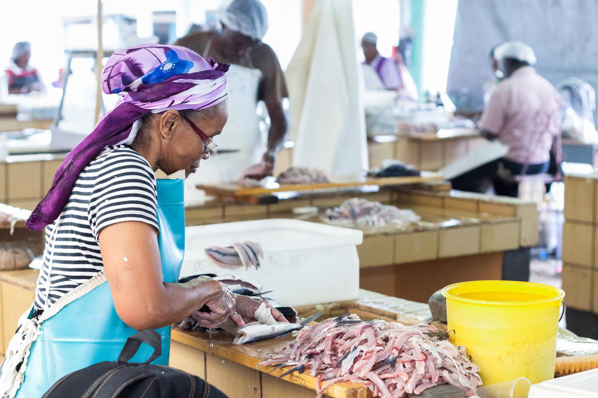 Förbereder färsk flygfisk för försäljning på Bridgetown Fish Market.