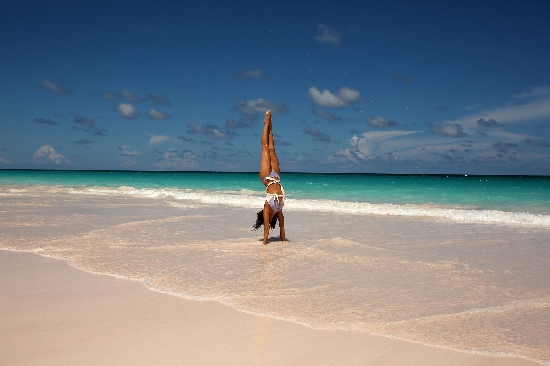 A woman doing yoga on the pink sand beaches of the Bahamas
