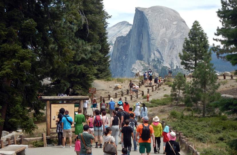 Tourists walk to Glacier Point with a background view of Half Dome at Yosemite National Park. 