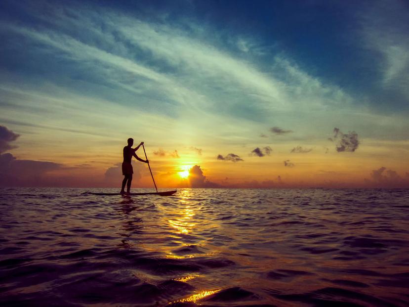 Young man stand-up paddleboarding during a beautiful sunrise in Mexico