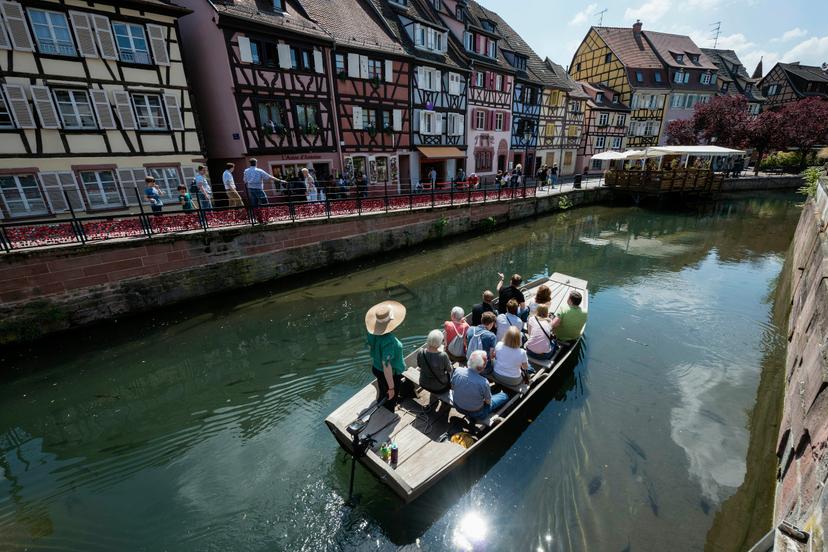 Colmar, Alsace, France -May, 09, 2022: Tourists glide by boat through the canal and admire the architecture of the half-timbered houses. The city is known for its beautiful half-timbered houses and canals