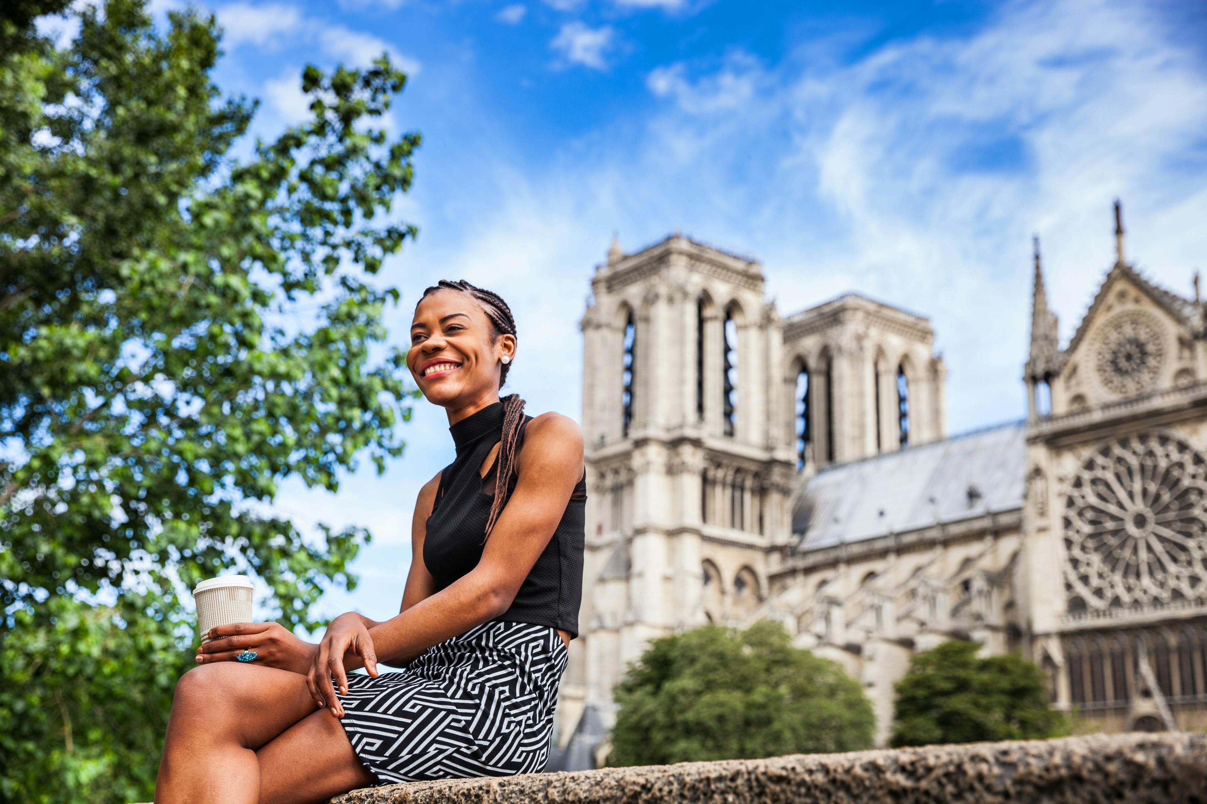 Young black woman walking in Paris near Notre Dame cathedral.