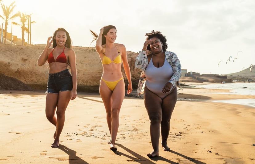 Happy multiracial females with different body size having fun walking on the beach during summer holidays