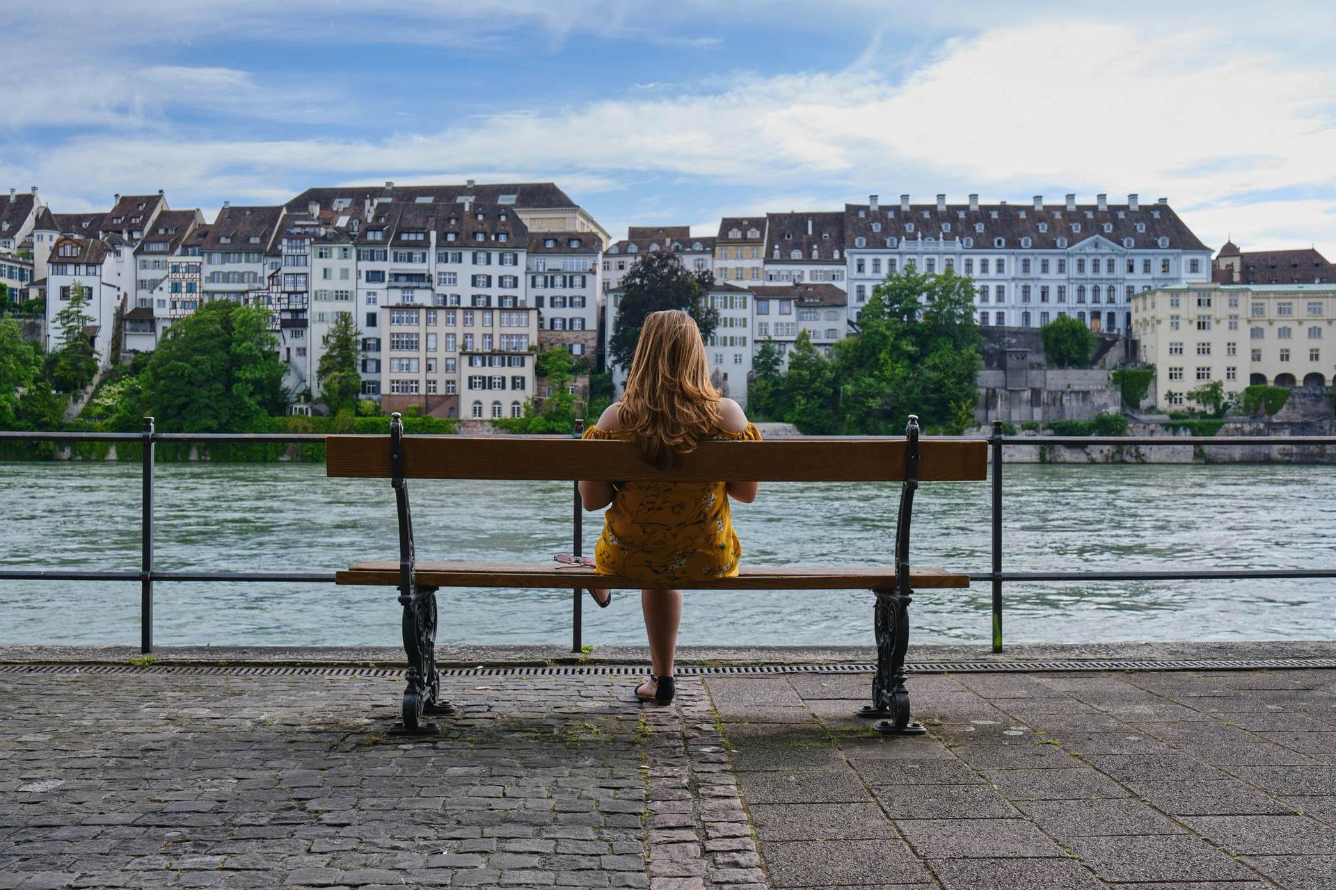 Woman sitting on a bench next to the Rhine River in Basel, Switzerland