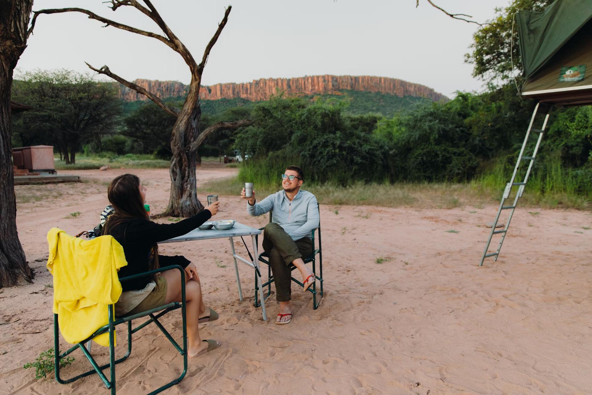 Två resenärer skålar på sin camping i Namibia