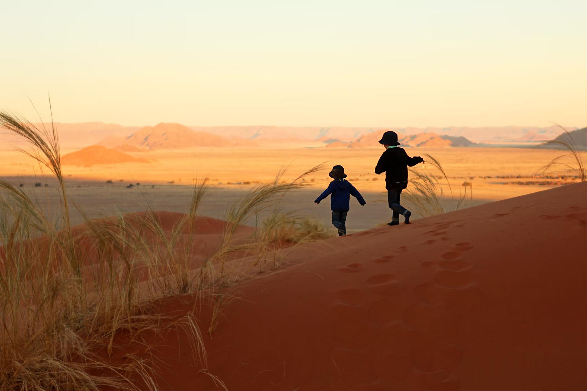 Två barn som springer nerför sanddynerna i Sossusvlei Namibia