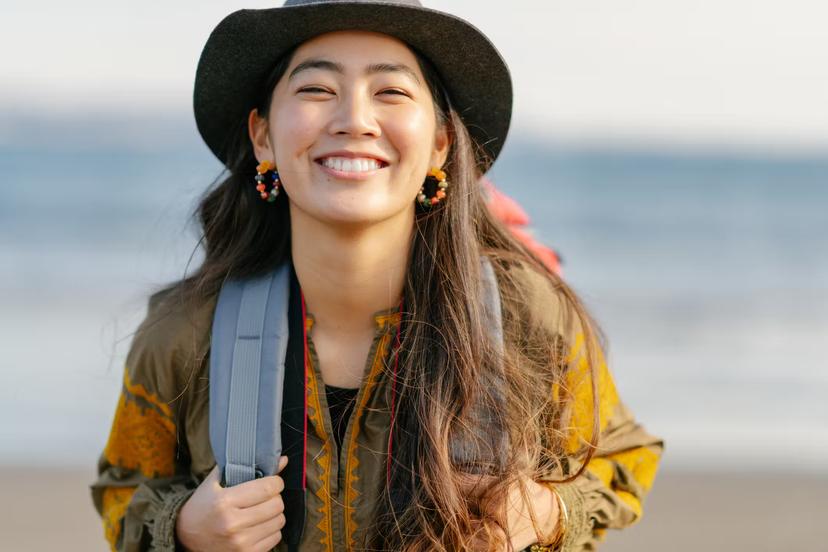 A close-up portait of a happy female solo traveller at the beach.