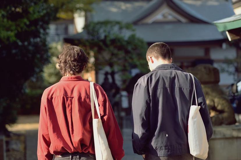 Two young men walking towards a shinto shrine on a sunny day.