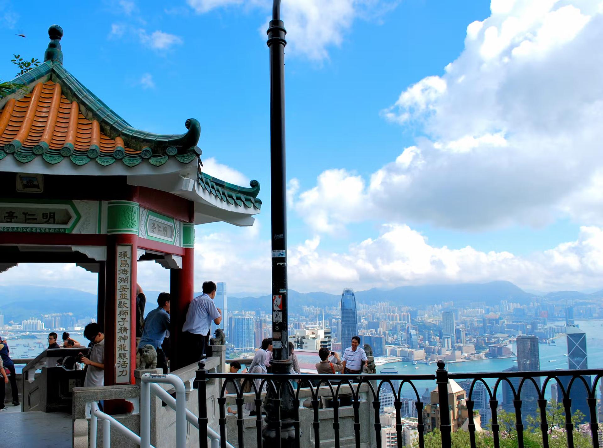 Människor poserar för foton vid utsiktspunkten Victoria Peak, med höghus i Hong Kong bakom sig
