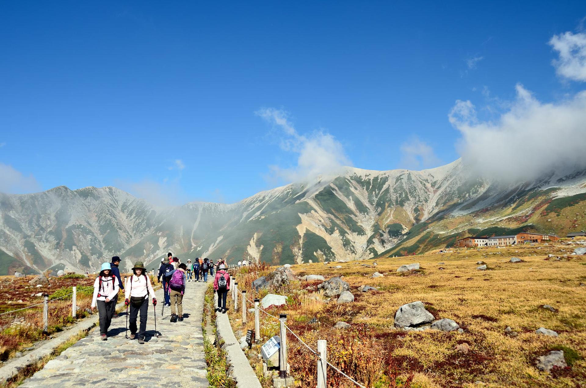 Hikers trek along a stone path in the Japanese mountains. 