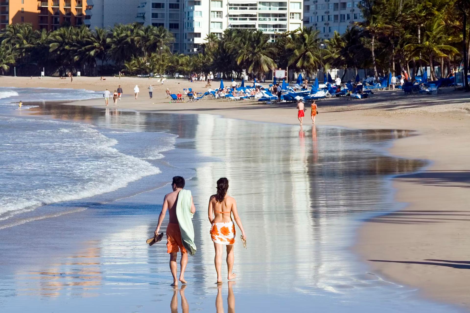 A beach couple walking on the sand.