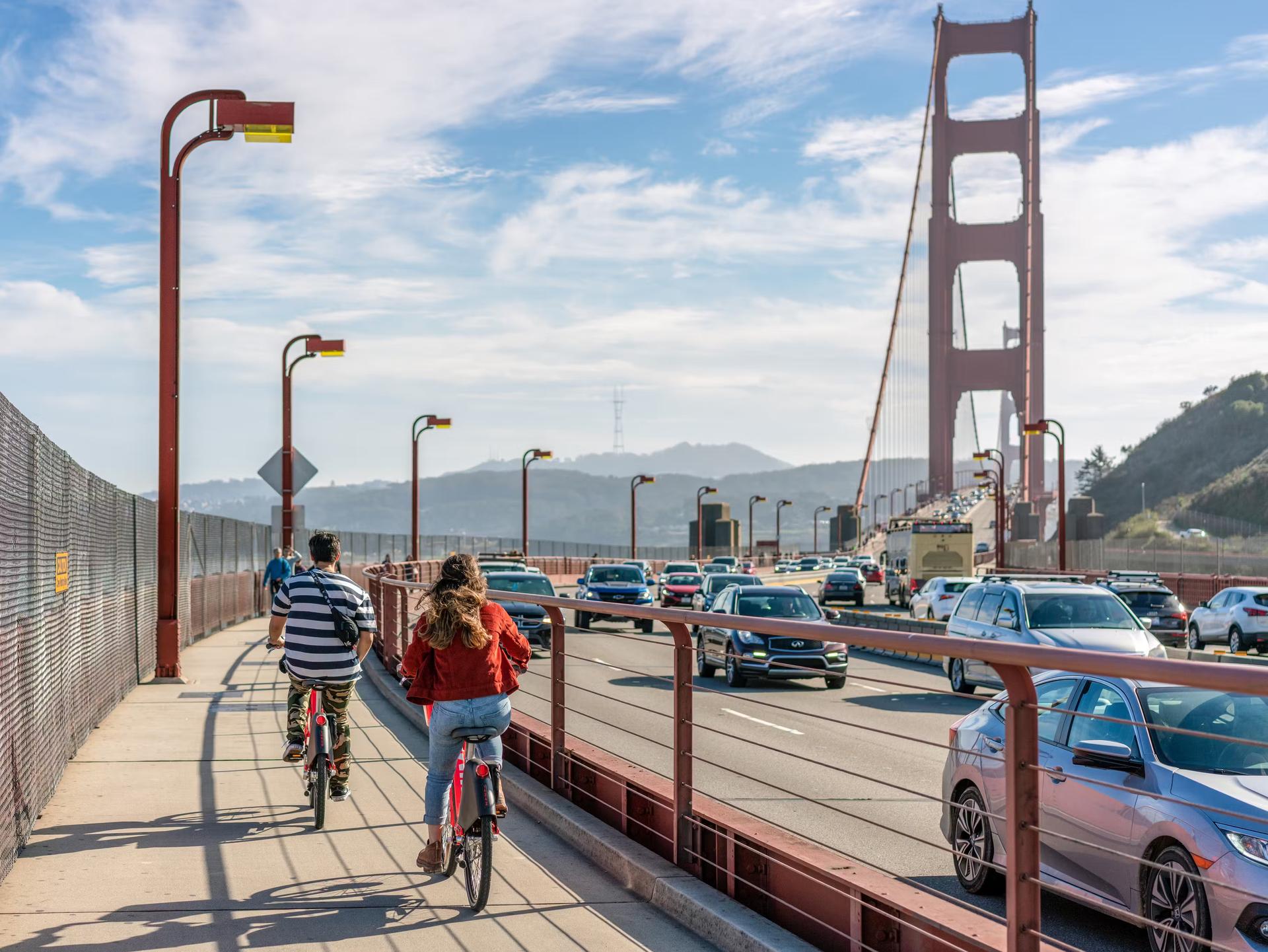 A rear view of people cycling towards the Golden Gate Bridge, heading in the direction of San Francisco