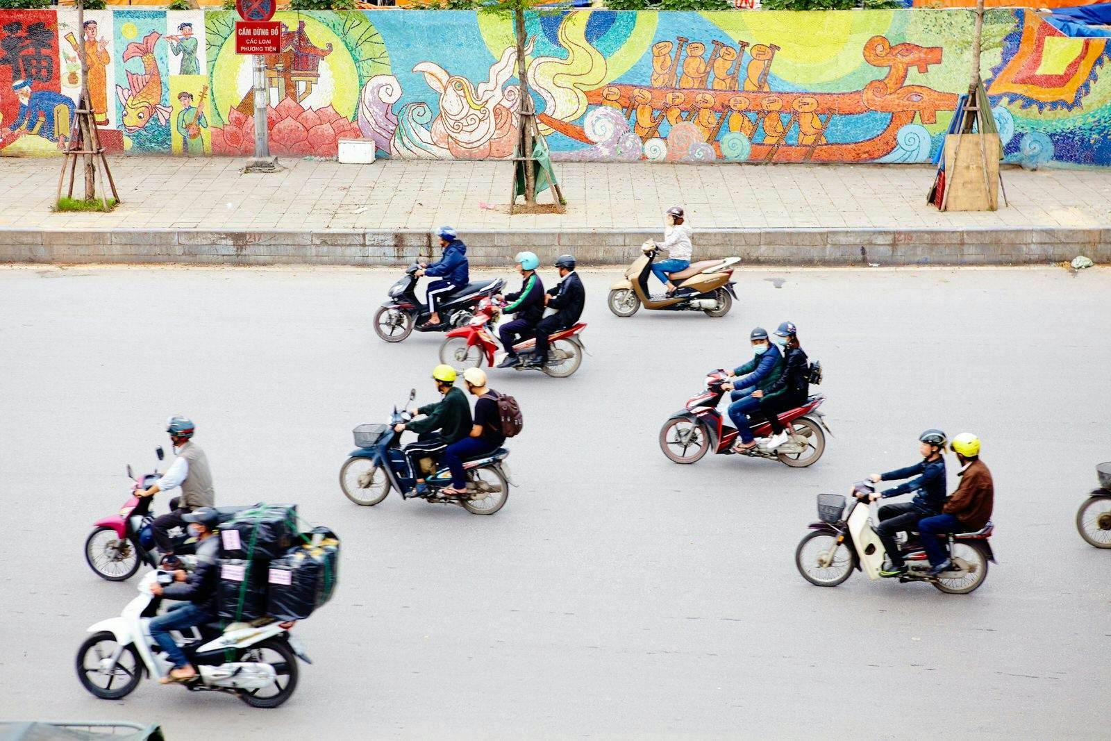Aerial view of a selection of mopeds driving down a concrete street in Hanoi