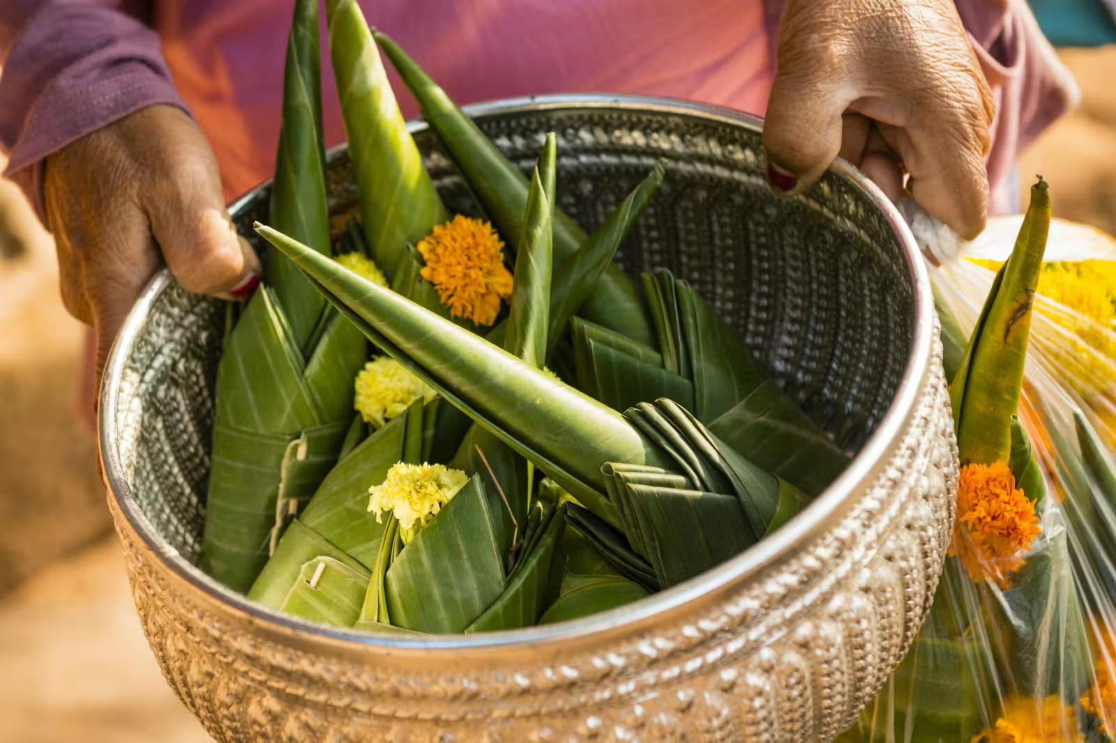 A woman holds a basket full of marigold offerings