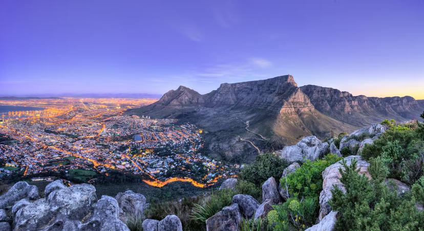 Looking down over Cape Town from the top of Lions Head peak, this view shows table mountain warmly lit in afterglow of sunset. The streets of the city are alight with the headlights of cars © Quality Master / Shutterstock