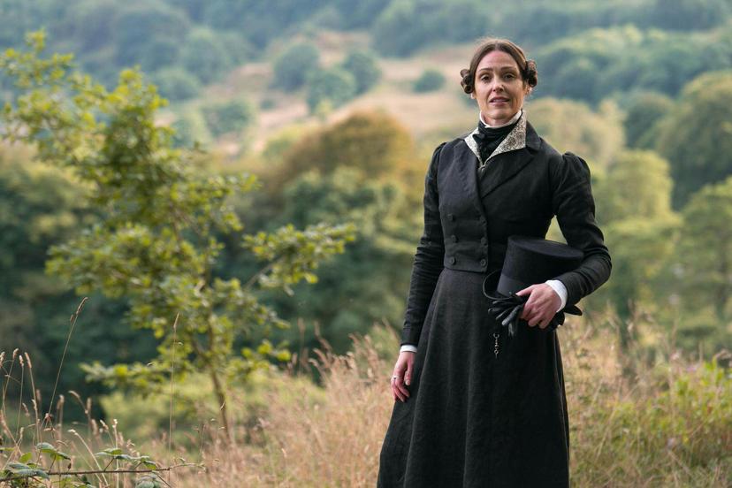 Actor Suranne Jones dressed as Anne Lister, stands holding her top hat with the Yorkshire landscape as a backdrop