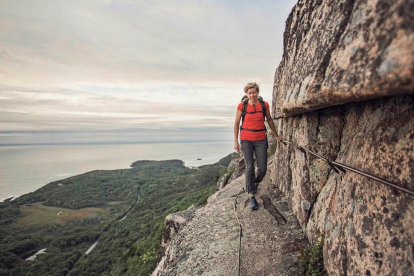 A woman hikes along the cliff edge in Maine's Acadia National Park, Maine