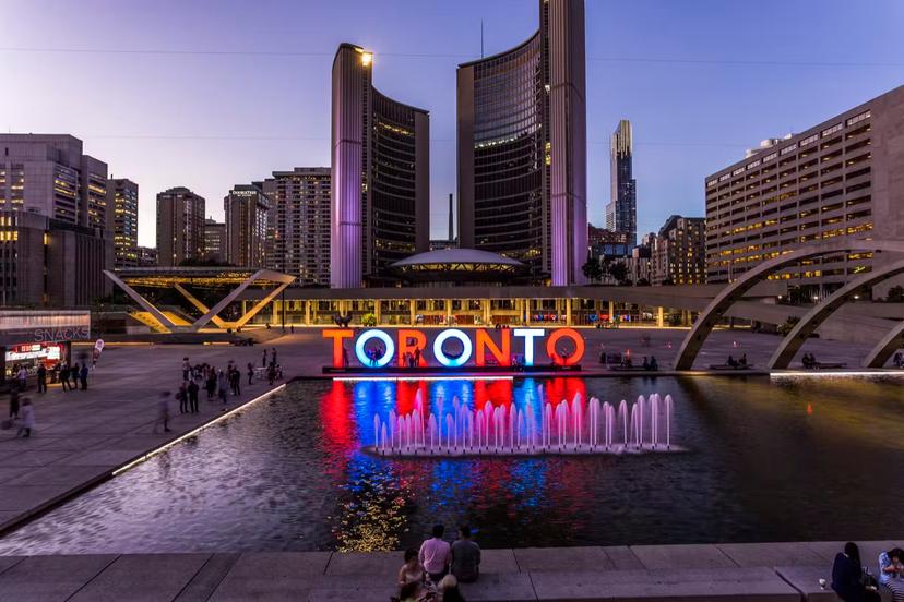 The Toronto sign at Nathan Phillips Square is lit up in red and white and blue, and reflected in a pool, as the sun goes down in Toronto; Weekend in Toronto