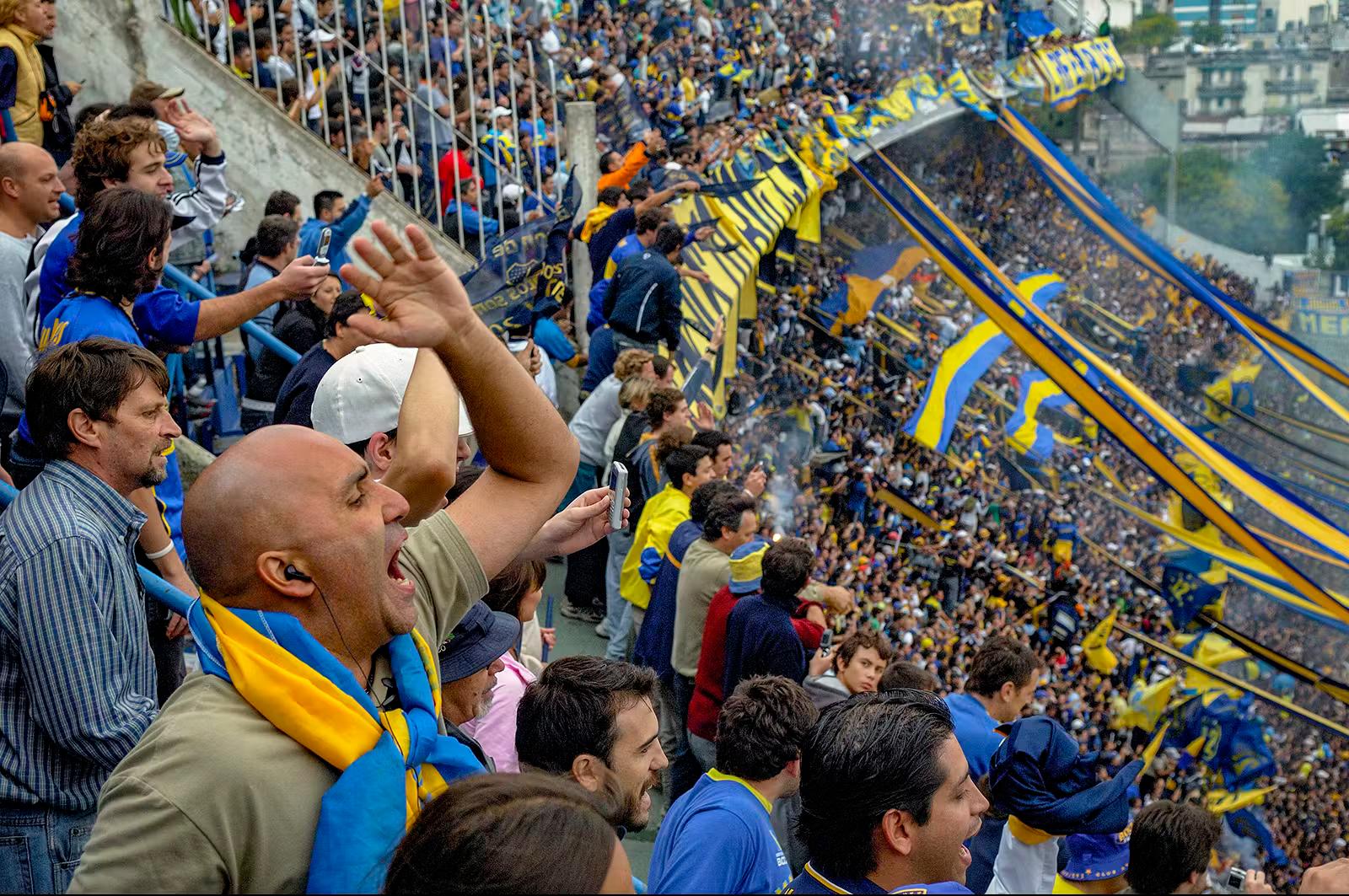 Fans klädda i blått och gult hejar på sitt lag på La Bombonera Stadium i Buenos Aires, Argentina