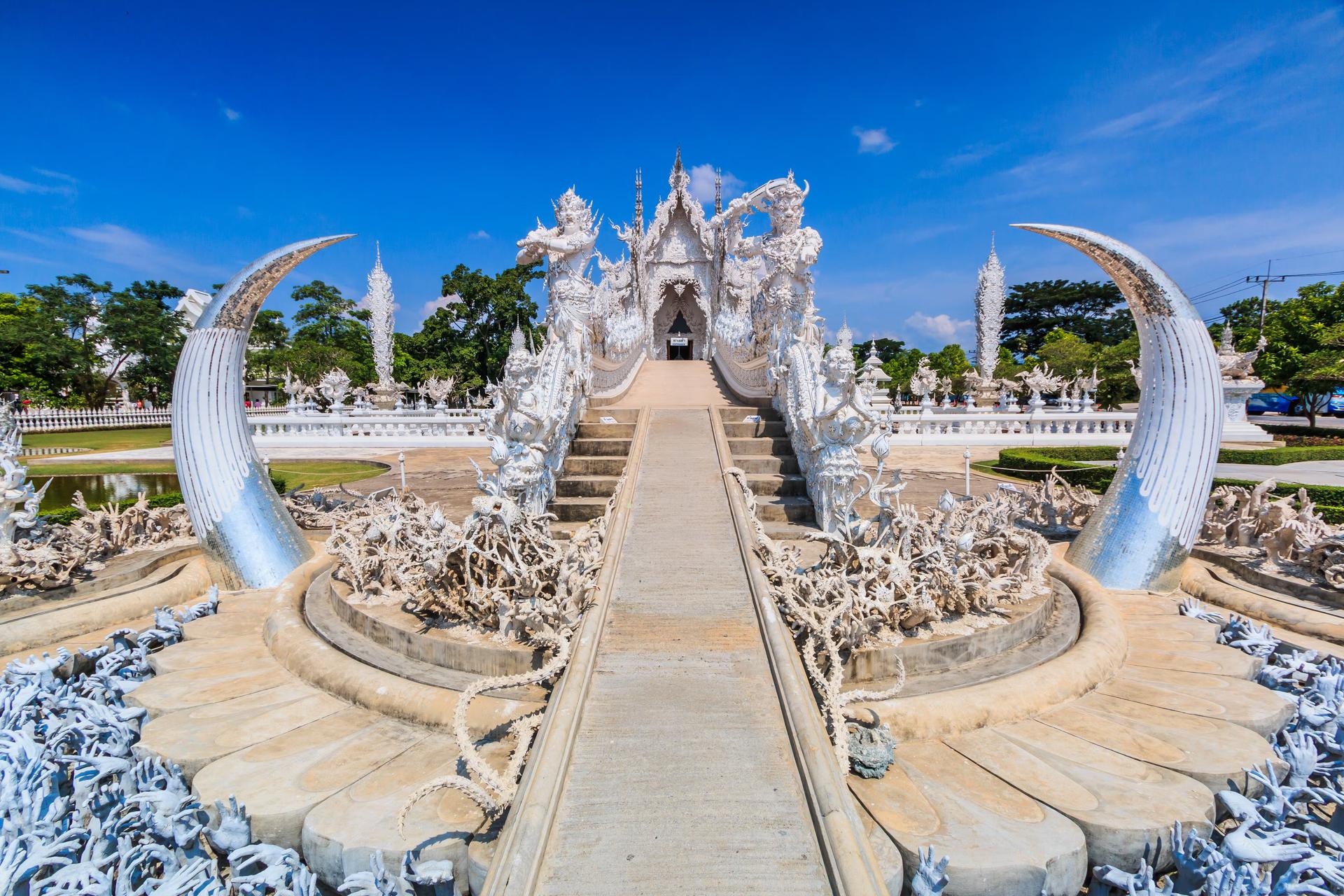 Ingången till Wat Rong Khun, en konstutställning i stil med ett buddhistiskt tempel i Chiang Rai.  Den smala stigen till tempelingången, som är ljust vit, går över en 