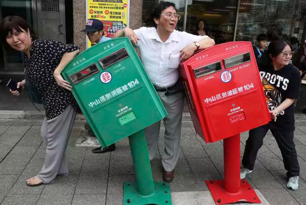 People pose for photographs next to a pair of roadside mailboxes that were uniformly bent by a falling signboard during Typhoon Soudelor earlier this month in Taipei, Taiwan. The damaged mailboxes have become celebrities in Taiwan.